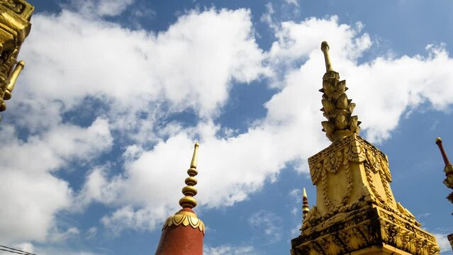 Decorative burial stupas in temple grounds. Dynamic zoom time lapse with motion control through structure during monsoon clouds in blue sky.
