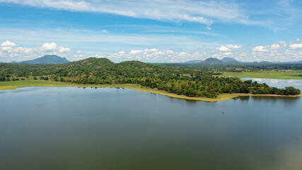 Fototapeta na wymiar Aerial view of tropical landscape with lake and valley with tropical forest. Sorabora lake, Sri Lanka.