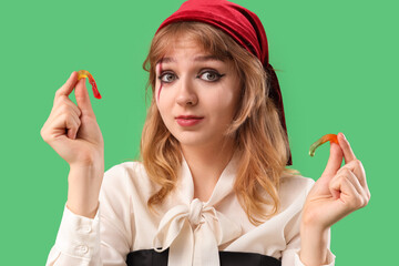 Young woman dressed for Halloween as pirate with jelly worms on green background, closeup