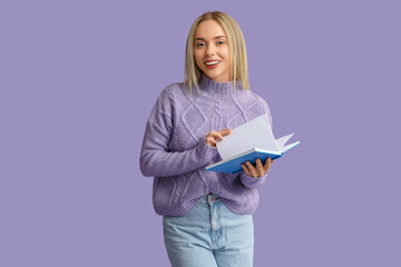 Beautiful young happy woman with book on lilac background
