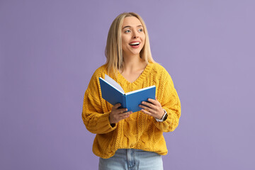 Beautiful young happy woman with book on lilac background