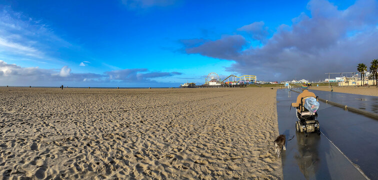 Panoramic view of a man in a wheelchair walking along the bike path of Santa Monica Beach in California, which meets the Venice Beach in Los Angeles, USA.