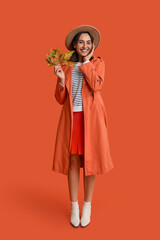 Beautiful young woman with autumn leaves on red background