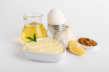 Bowl of fresh mayonnaise and ingredients on white background