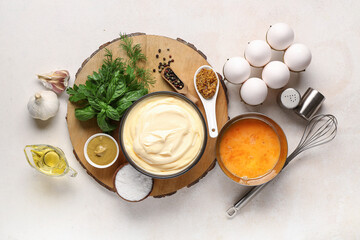 Bowls of fresh mayonnaise and ingredients on white background