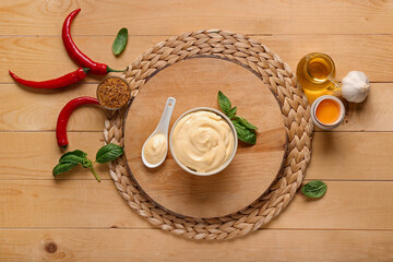 Bowl and spoon of fresh mayonnaise and ingredients on wooden background
