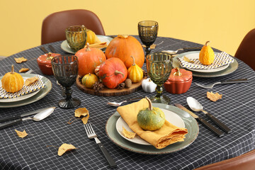 Beautiful table setting with autumn leaves and pumpkins in dining room, closeup
