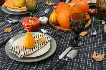 Beautiful table setting with autumn leaves and pumpkins in dining room, closeup