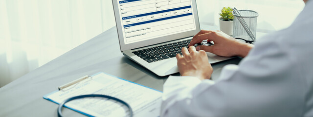 Doctor carefully review detailed medical report on laptop and diagnosing illness for effective healthcare treatment plan for patient in doctor office. Professional medical evaluation. Neoteric