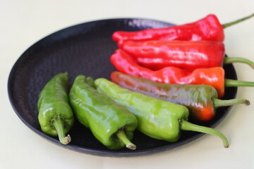 green to red colors chilli peppers on white plate