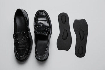 Pair of stylish female shoes and orthopedic insoles on light background