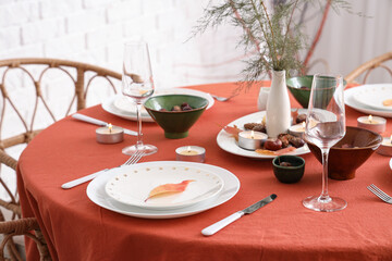 Autumn table setting with burning candles and dry leaves, closeup
