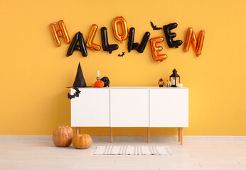 Word HALLOWEEN made of balloons on yellow wall in living room interior