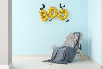 Word BOO made of balloons with paper bats and armchair in living room