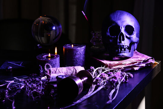Witch's magic attributes with skull on dark table, closeup