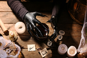Witch with crystal ball on dark wooden table, top view