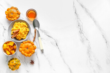 Bowl of tasty millet porridge with pumpkin and honey on white marble background