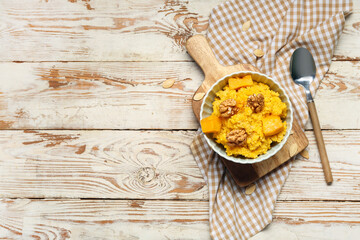 Bowl of tasty millet porridge with pumpkin on white wooden background