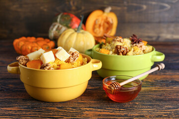 Pots of tasty millet porridge with pumpkin and honey on wooden background