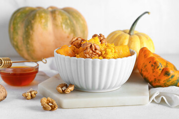 Bowl of tasty millet porridge with pumpkin on white background