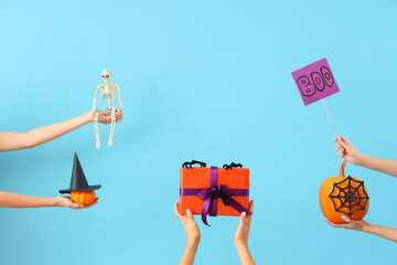 Fototapeta premium Women with Halloween gifts, pumpkins and decor on blue background