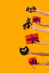 Women with Halloween gifts and paper decor on yellow background