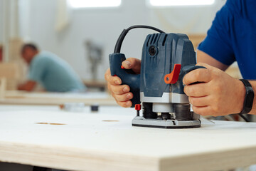 Close up of male carpenter working with piece of wood in a workshop