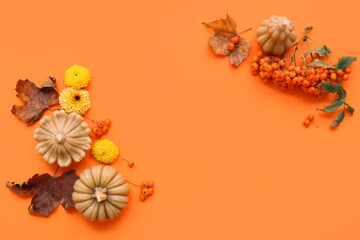 Frame made of candles in shape of pumpkin, flowers and autumn leaves on orange background