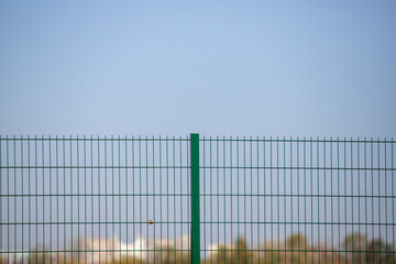 Green metal mesh against the background of nature and sky