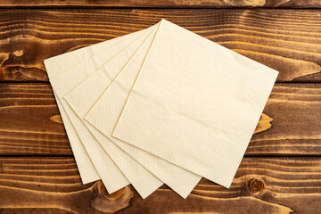 Stack of paper square napkins on brown wooden background