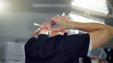 Surgeon, hands and man tie mask in hospital, operating room and medical theater with safety...