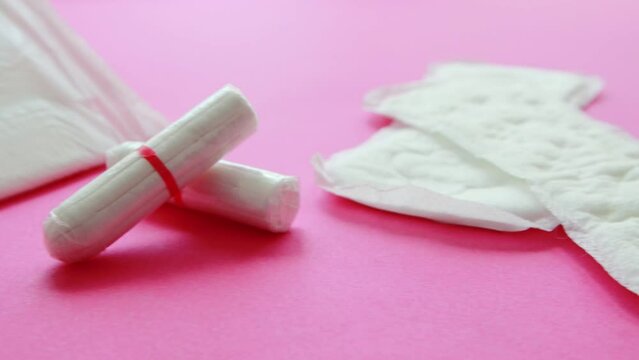 Different types of women's pads and tampons lie on a pink background. Koznept protection of girls from menstruation in gynecology. Copy space for text