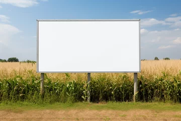 Zelfklevend Fotobehang Blank large billboard on the side of the road. Agricultural field and blue sky as background. Advertisement and marketing concept. Mockup banner for public publicity.  © Anna