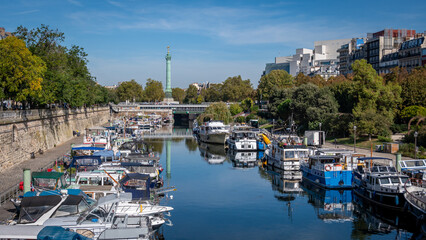 Paris, France: Le port de plaisance de Paris Arsenal, sur le canal Saint-Martin, avec la place de la Bastille et la colonne de Juillet à l'arrière-plan - obrazy, fototapety, plakaty