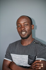 Portrait of a black man with his arms crossed on a gray background.