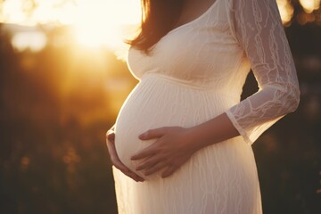 Close-up of pregnant woman with hands on her belly outdoors - obrazy, fototapety, plakaty