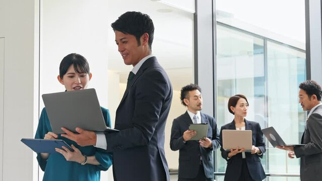 デジタルデバイスを持って打ち合わせするビジネスパーソンのグループ