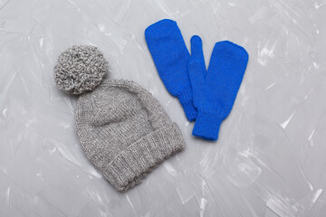 Hats, gloves and a scarf on a textured background. Warm clothes for autumn and winter in the form of hats, gloves and a scarf. Fashionable set of clothes made of hats and gloves