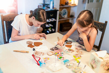 Culinary workshops. Children decorating gingerbread cookies with glaze on table at home - 661332649
