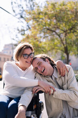 portrait of a happy couple of a man and woman using wheelchair laughing looking at camera, concept of friendship and technology of communication