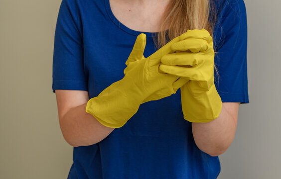 Kobieta zakłada żółte gumowe rękawiczki ochronne do sprzątania 