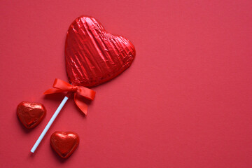 Heart shaped chocolate candies on red with room for text