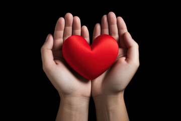 Fototapeta premium Hands tenderly holding a red heart on black background