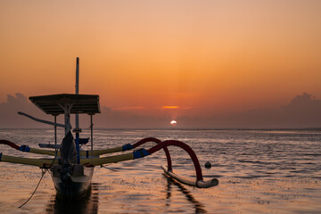 Lev&eacute; du soleil avec une pirogue &agrave; balancier indon&eacute;sienne sur la plage de Karang &agrave; Bali. 