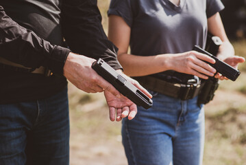 A girl learns to shoot a pistol at a shooting range with an instructor