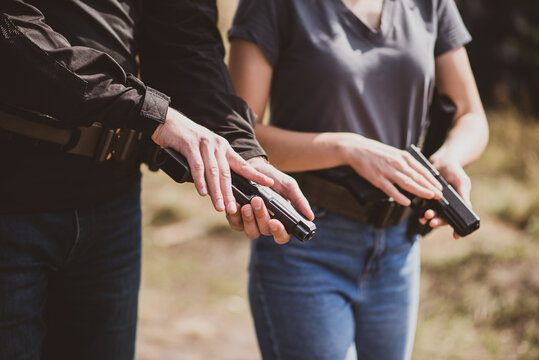 A weapons instructor teaches a girl to shoot a pistol at a firing range