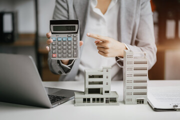 home loan officer uses a calculator with a house plan loan real estate or property.