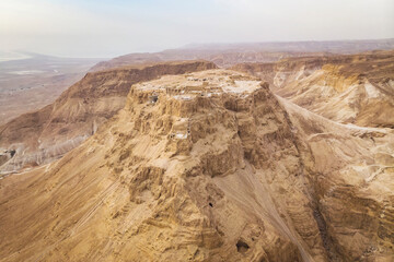 Scenic view of the cliff with a flat platform on the top shot from the air. Ancient isolated settlement on plateau in Judean desert, Israel. Archaeological works. Ruins of ancient fortification