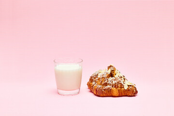 Sweet, fresh, crispy almond croissant with glass of milk isolated over pink background. Yummy breakfast. Concept of food, bakery, breakfast ideas, taste, freshness. Poser. Copy space for ad
