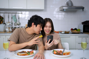 Young couple is shopping online in kitchen.